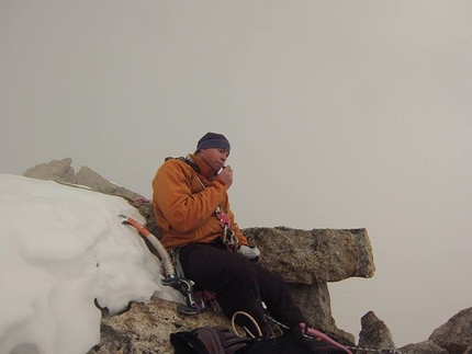 Tom Ballard, Petit Dru, Monte Bianco - Tom Ballard mangia un po' di cioccolata in cima, stanco dopo 8 ore di scalata. Inizia a nevicare...